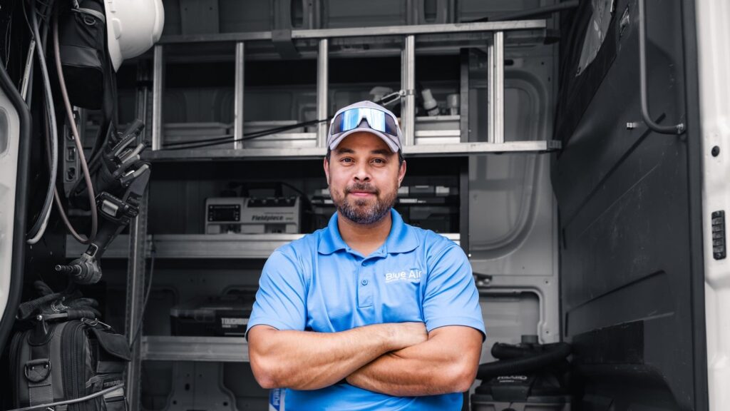 Blue Air technician standing in the service van