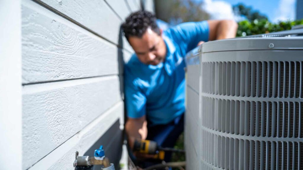 Blue Air technician servicing an outdoor condenser beside a home
